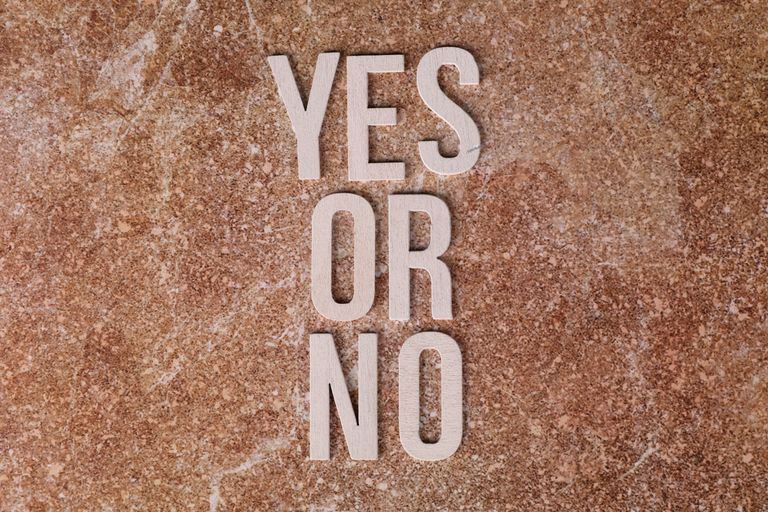 Wooden letters on marble background spell 'YES OR NO' symbolizing choices.